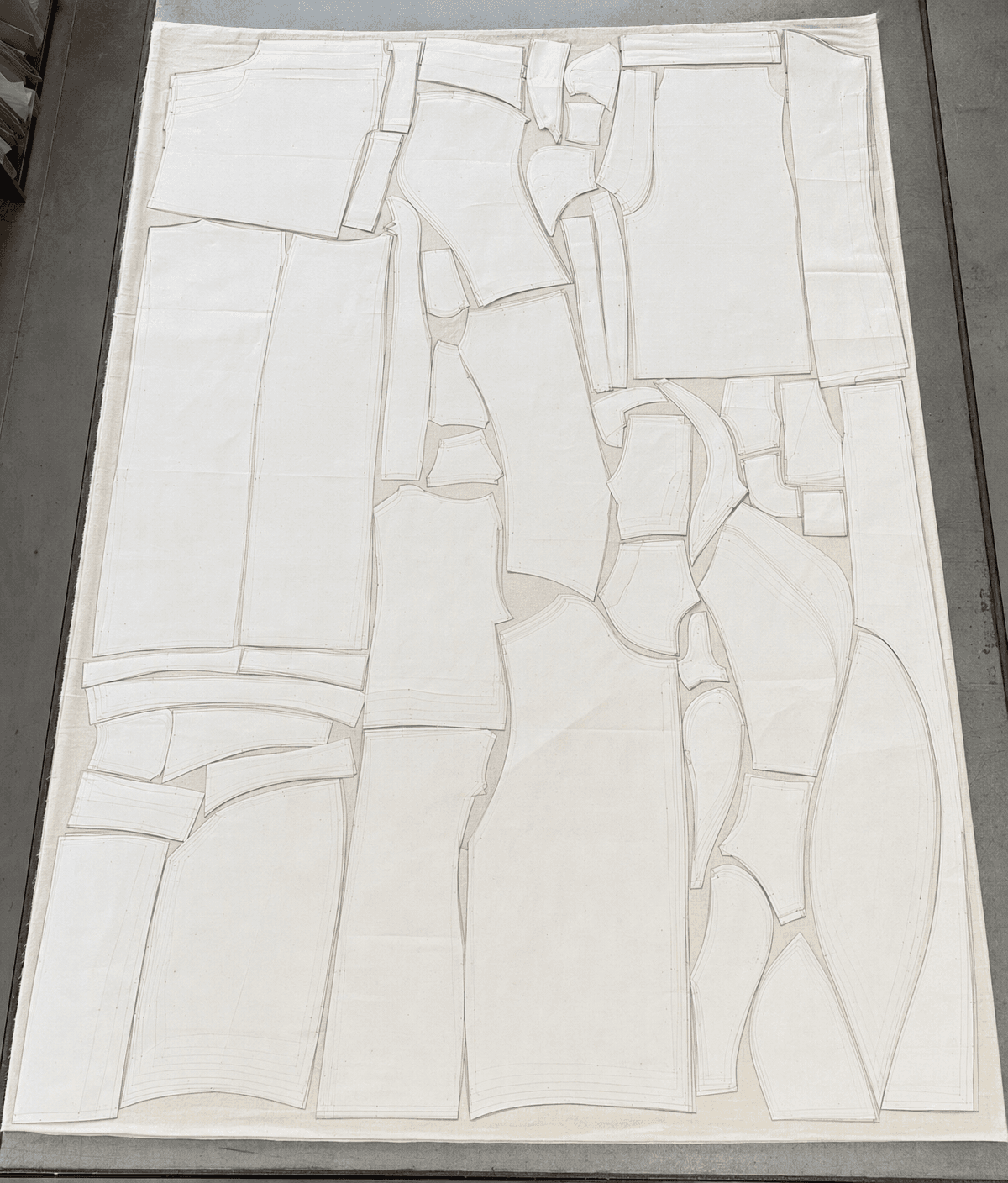 Pattern pieces nested and marked onto fabric on a cutting table, every seam drawn