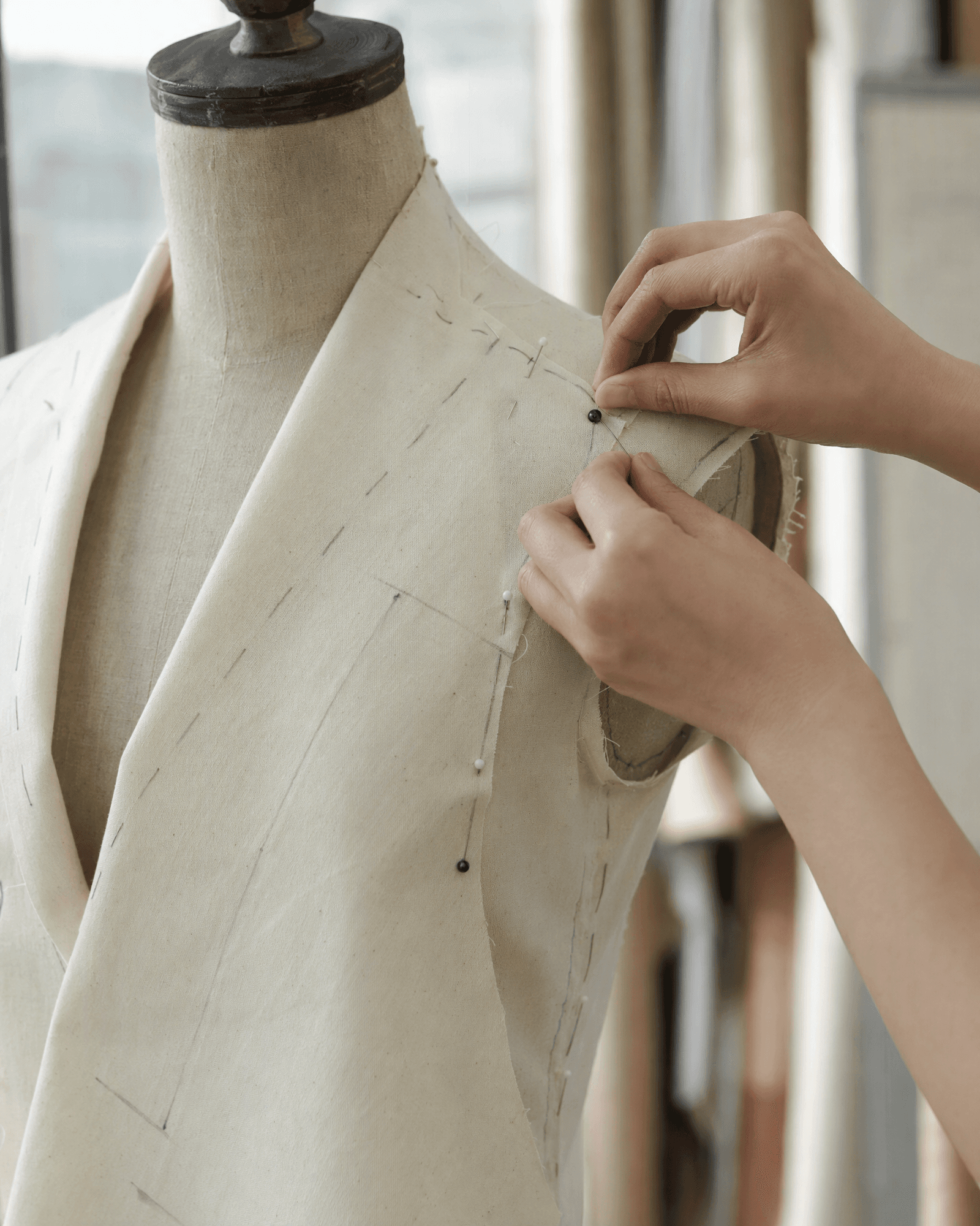 A calico toile being pinned at the shoulder seam on a tailor's dress form
